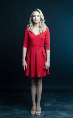 Kırmızı elbiseli güzel sarışın kadın. Stüdyo. koyu arkaplan.