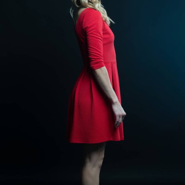 Siyah arka planda poz veren kırmızı elbiseli güzel bir kadın.