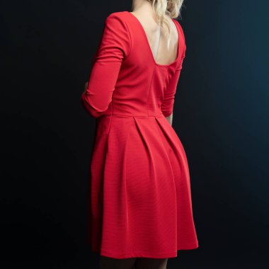 Siyah arka planda poz veren kırmızı elbiseli güzel bir kadın.