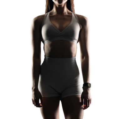 Beyaz arka planda spor giyimli genç bir kadın.