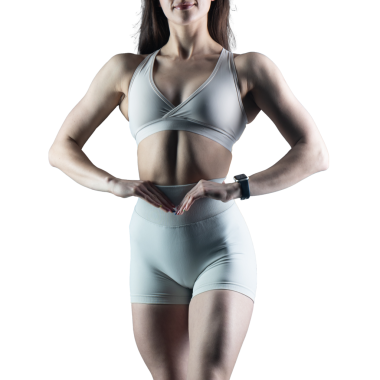 Beyaz arka planda spor giyimli genç bir kadın.