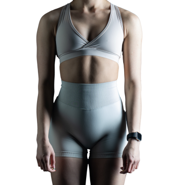 Beyaz arka planda spor giyimli genç bir kadın.