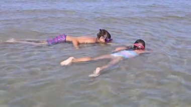 İki çocuk hoş bir sualtı macerasına girişiyor, berrak mavi sularda yüzüyor ve şnorkelle yüzüyor, canlı bir suda keşif ve neşe ruhunu yakalıyorlar.