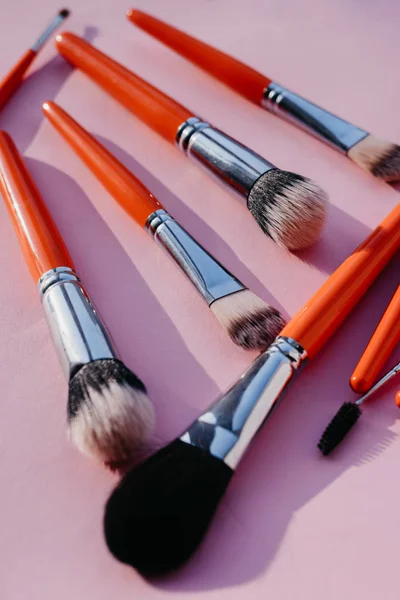 Set of brushes for makeup in orange color on a pink background — Stock Image Set Brushes Makeup Orange Color Pink Background Stock Picture
