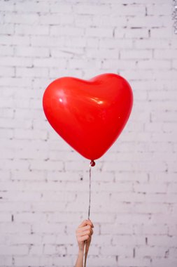 Kadın el tutma kırmızı kalp balon ve tuğla duvar stüdyosu arka planda poz, Doğum günü partisi kavramı 
