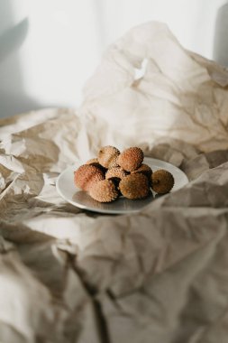 Kağıt arka planda Lychee meyveler ile seramik beyaz plaka