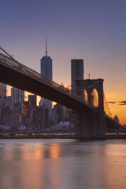 Arka planda New York silueti olan Brooklyn Köprüsü, günbatımında çekilen.