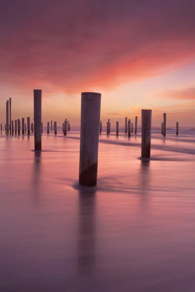 Ξύλινων Στύλων Στέκεται Στο Σερφ Στην Παραλία Φωτογράφησε Ηλιοβασίλεμα — Φωτογραφία Αρχείου