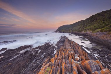 Sunrise over the rocky coastline of the Tsitsikamma section of the Garden Route National Park, South Africa. clipart
