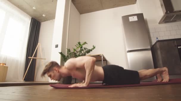 Спортсмен делает боковую стойку на коврике в домашней комнате — стоковое видео