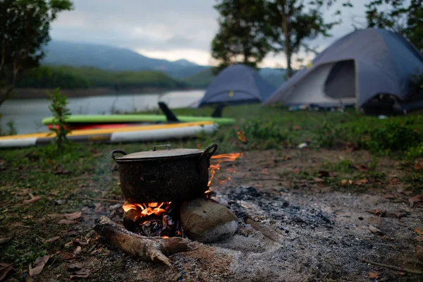 キャンプや朝のピクニックにキャンプファイヤーで鍋を沸騰 フィールド条件で調理 荒野やアウトドア キャンプのテントに行くと 薪を使用してストーブは薪に夕食を作って — ストック写真