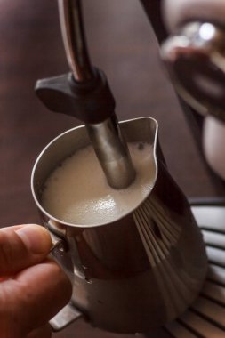 Profesyonel barmen süt kapuçino için Isınma. Barista kahve makinesi latte sanat macchiato için kullanma. Tonlu görüntü.