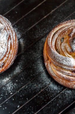 Kek pasta krizi bir rulo şeklinde koyu arka plan ve antika bir ızgara üzerinde pudra şekeri serpilir. Paskalya ve Noel pişirme. Üstten Görünüm, metin, yer yakın çekim.