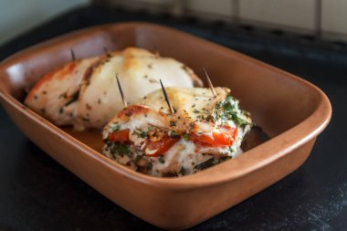 Fırında tavuk fileto yumuşak peynir, domates ve bir seramik tabak pişirme otlar ile doldurulmuş. Doğru yararlı sağlık gıda, beslenme kavramı.