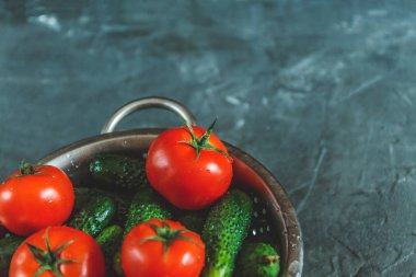 ham bütün karanlık bir beton zemin üzerine bir kevgir içinde domates ve salatalık yıkadım. Yukarıdan görüntüleyin. Düz yatıyordu.