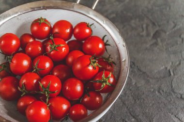 ham bütün karanlık bir beton zemin üzerine bir kevgir içinde kiraz domates yıkanır. Yukarıdan görüntüleyin. Düz yatıyordu.