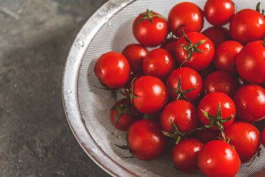 ham bütün karanlık bir beton zemin üzerine bir kevgir içinde kiraz domates yıkanır. Yukarıdan görüntüleyin. Düz yatıyordu.