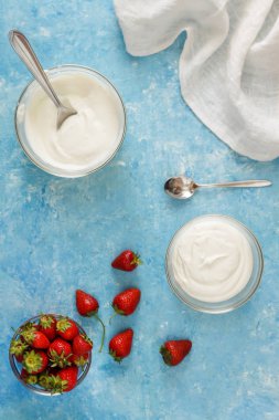 Organik yoğurt bir kase taze çilek mavi bir beton zemin üzerinde kesti. Üstten görünüm ve yakın çekim. Flatlay.