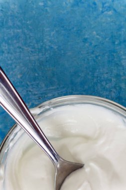 Bir kase bir kaşıkla, mavi taş masa üstü görünümü yakın çekim Yunan yoğurt