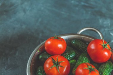 ham bütün karanlık bir beton zemin üzerine bir kevgir içinde domates ve salatalık yıkadım. Yukarıdan görüntüleyin. Düz yatıyordu.