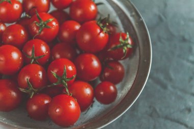 ham bütün karanlık bir beton zemin üzerine bir kevgir içinde kiraz domates yıkanır. Yukarıdan görüntüleyin. Düz yatıyordu.