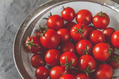 ham bütün karanlık bir beton zemin üzerine bir kevgir içinde kiraz domates yıkanır. Yukarıdan görüntüleyin. Düz yatıyordu.