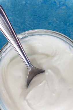 Bir kase bir kaşıkla, mavi taş masa üstü görünümü yakın çekim Yunan yoğurt