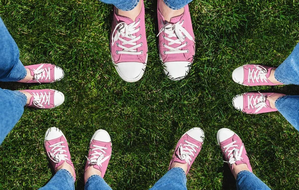 Collage of legs in old pink sneakers on green grass. View from above. The concept of youth, spring and freedom. Isolated on white background.