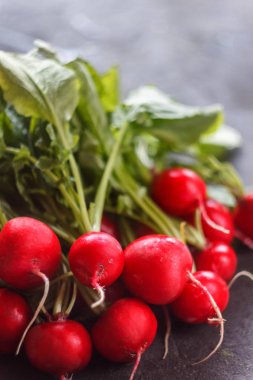 Karanlık bir arka plan üzerinde bir kevgir içinde yıkanmış taze sulu kırmızı turp