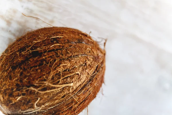 Coco inteiro sobre um fundo de madeira branco . — Fotografia de Stock