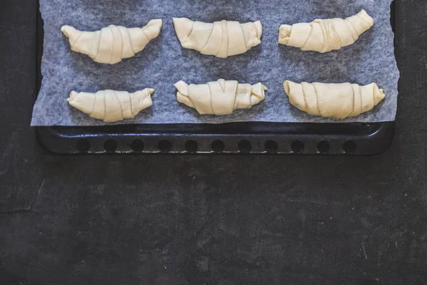 Råa croissanter med choklad på en plåt innan bakning. T — Stockfoto