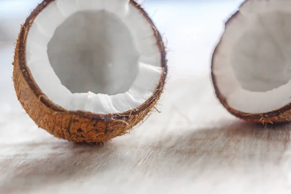 Duas metades de coco em um fundo de madeira branco claro, perto - — Fotografia de Stock