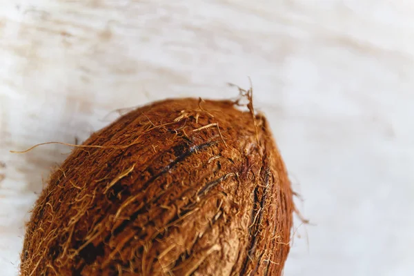 Coco inteiro sobre um fundo de madeira branco . — Fotografia de Stock