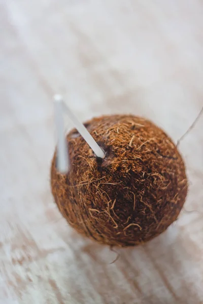 Весь кокос с коктейльной соломинкой на белом деревянном фоне — стоковое фото