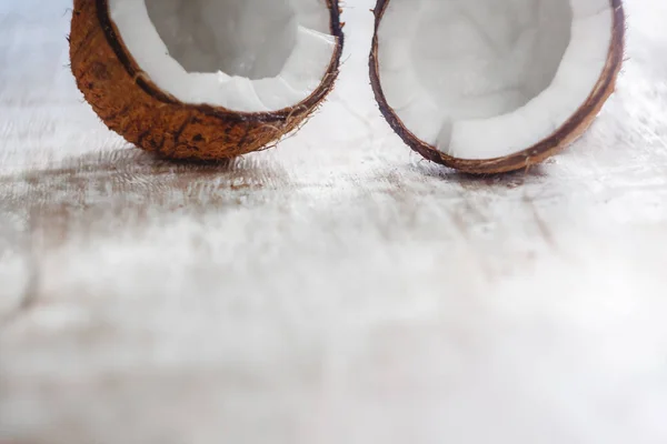 Duas metades de coco em um fundo de madeira branco claro, perto - — Fotografia de Stock