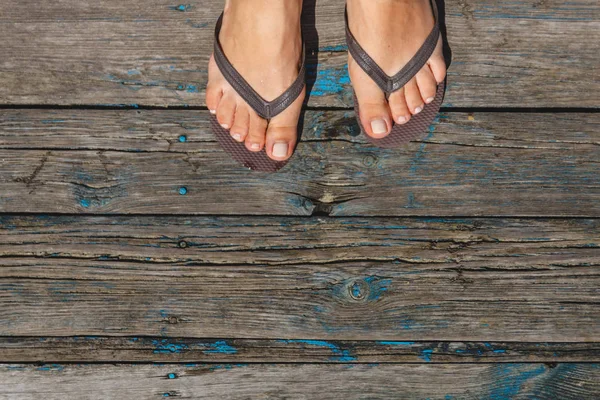 Вид сверху, фотография женских ног в пляжных флип-флопах на деревянном — стоковое фото