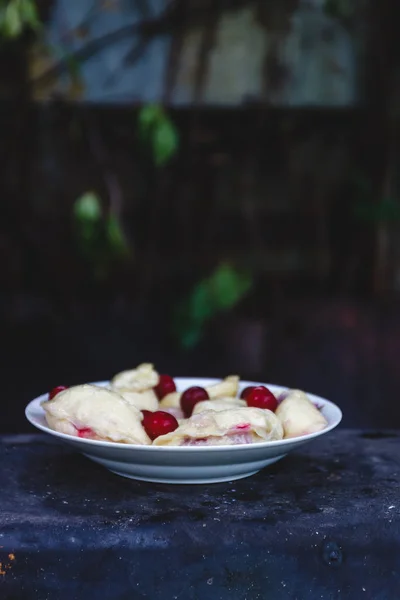 Dumplings con cerezas en un plato sobre un fondo retro oscuro . — Foto de Stock