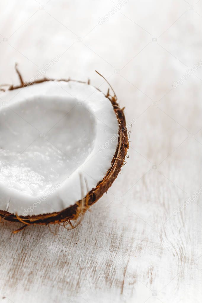 half coconut on a light white wooden background, closeup. Top vi