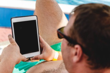 Gözlüklü genç bir adam elinde bir tablet tutuyor. Serbest