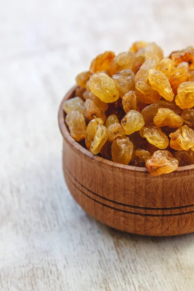 Light yellow raisins in a wooden bowl on a light white backgroun — Stock Photo, Image