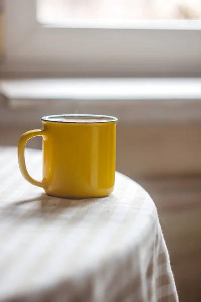Żółta filiżanka herbaty stoi na jasnym stole w słonecznym — Zdjęcie stockowe