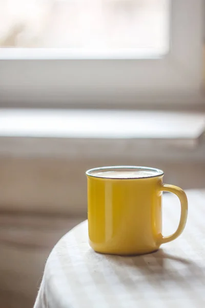 Una taza amarilla de té de café está sobre una mesa brillante en el soleado — Foto de Stock