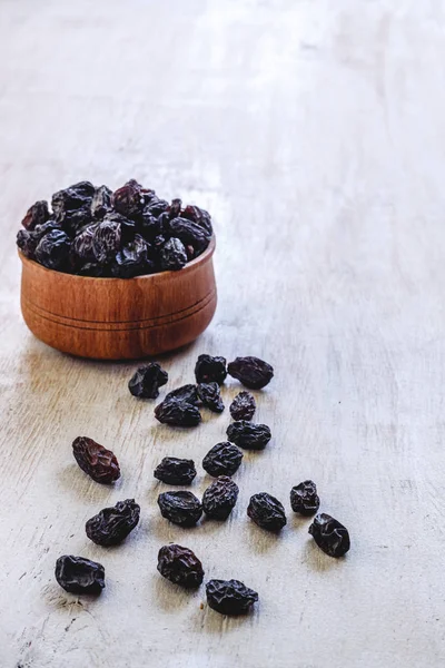 Dark blue raisins in a wooden bowl on a bright white background. — Stock Photo, Image