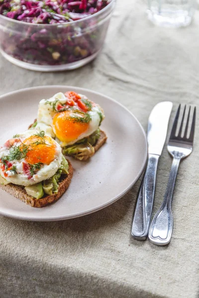 Pequeno-almoço servido de duas torradas com abacate, ovos fritos com veg — Fotografia de Stock
