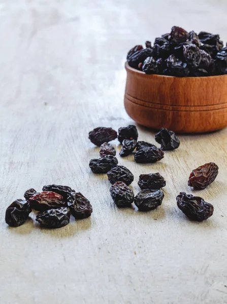 Dark blue raisins in a wooden bowl on a bright white background. — Stock Photo, Image