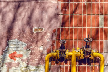 yüksek bir binanın duvarında borular üzerinde iki sarı vanalar