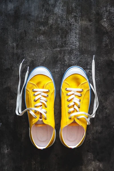Žlutooranžové tenisky s nevázanými tkankami na tmavém betonu — Stock fotografie