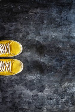 koyu beton sırt üzerinde bağcıkları ile sarı-turuncu spor ayakkabı