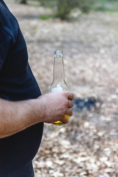 Een man met een grote buik houdt een fles bier — Stockfoto