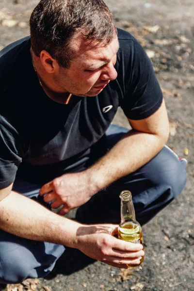 Een man met een grote buik houdt een fles bier — Stockfoto